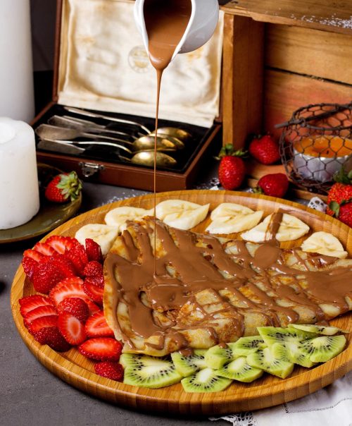 crepe with chocolate sauce and sliced strawberries kiwi and bananas